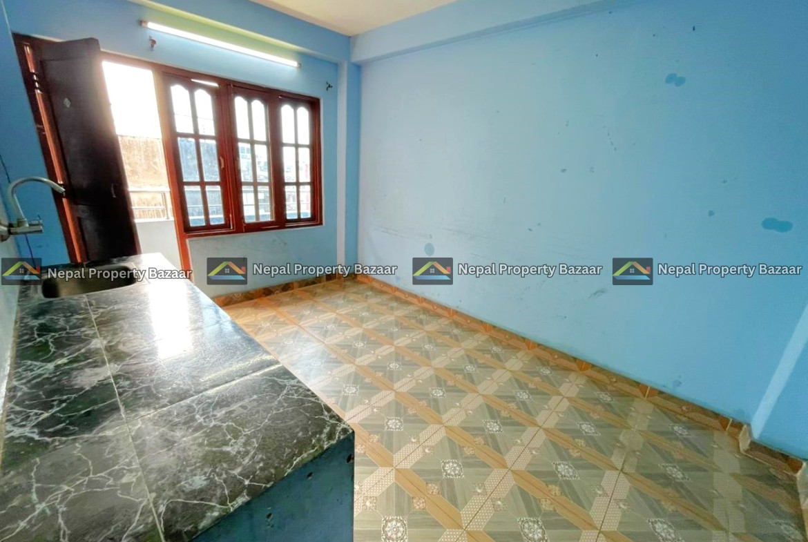 Small blue kitchen room with a dark cabinet by a large window, and a green marble countertop along the left wall, tiled floor.