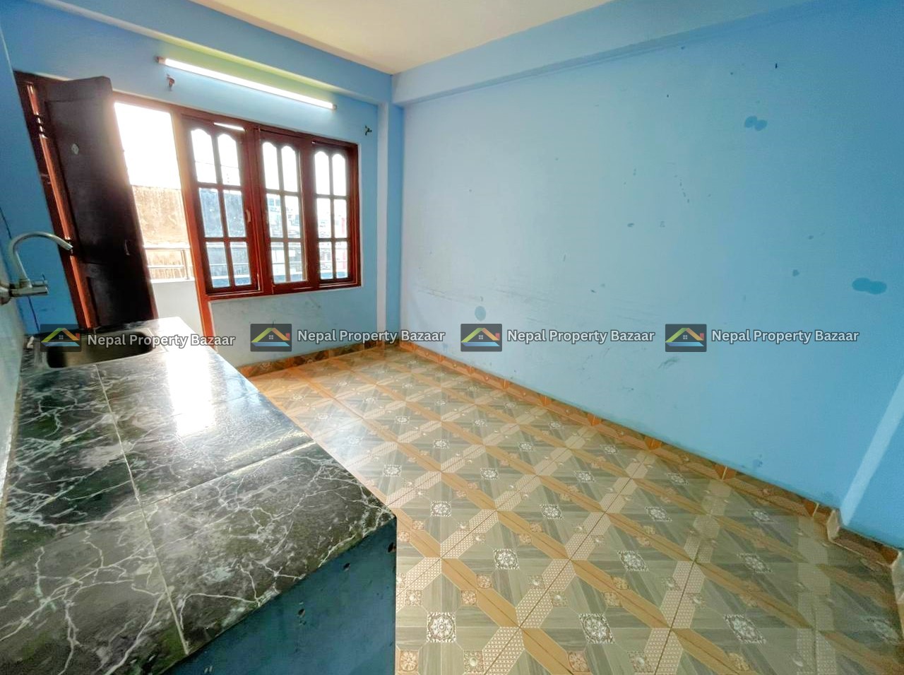 Small blue kitchen room with a dark cabinet by a large window, and a green marble countertop along the left wall, tiled floor.