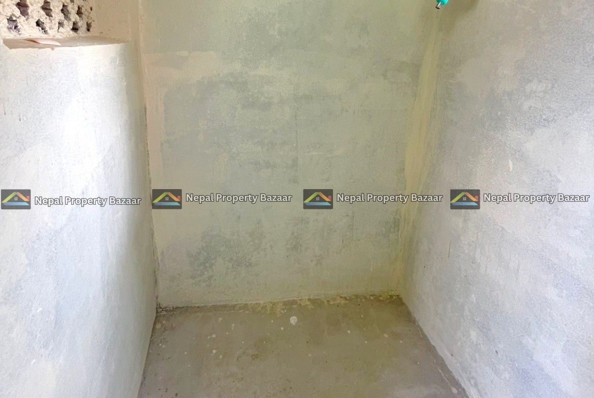 Small unfinished shower area with rough concrete walls, a green-handled faucet on the right, and a barred window near the top right.