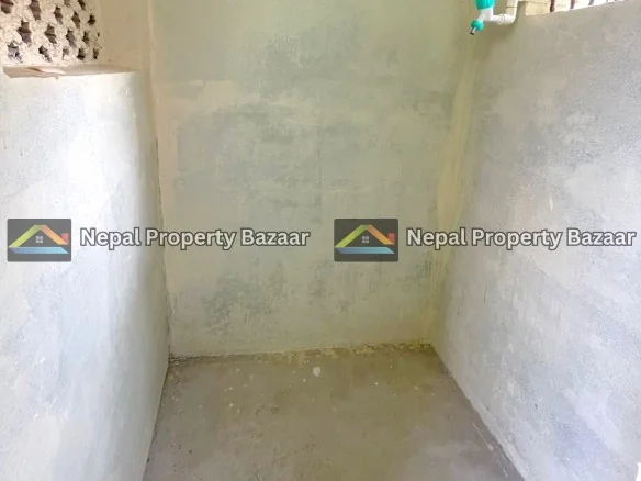 Small unfinished shower area with rough concrete walls, a green-handled faucet on the right, and a barred window near the top right.