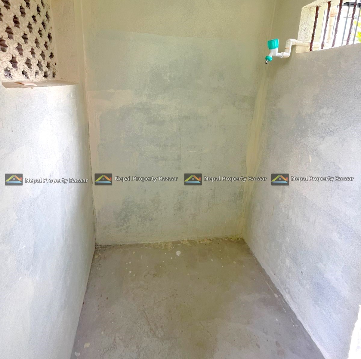 Small unfinished shower area with rough concrete walls, a green-handled faucet on the right, and a barred window near the top right.